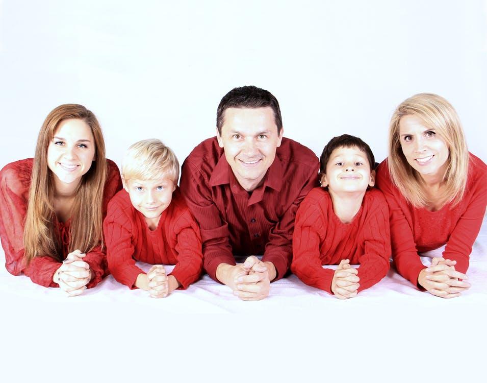rodzina leży razem na podłodze w czerwonych bluzach
